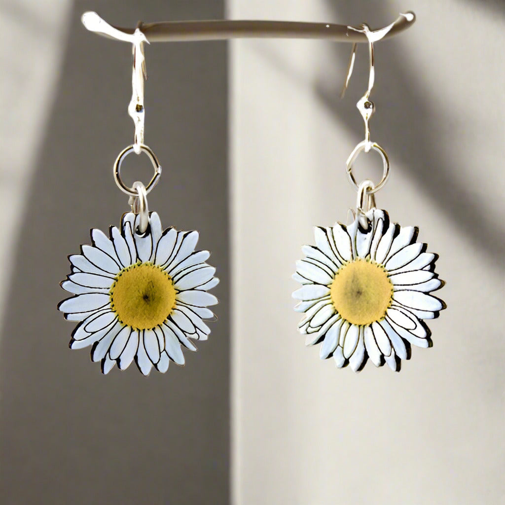 A pair of daisy blossom earrings with silver-finished ear wires, the flowers are designed using laser-cut wood with a natural wood back.