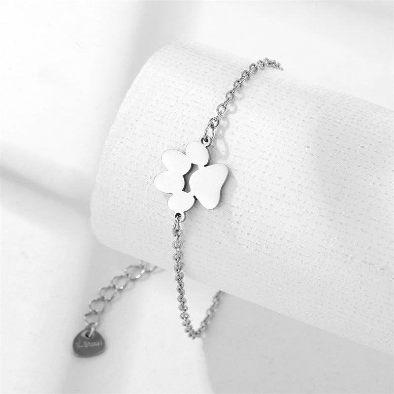 A stainless steel bracelet with a geometric pet's paw shape displayed on a white stand.