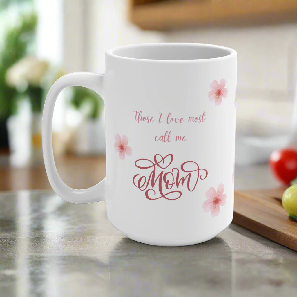 White mug with 'those I love most call me Mom' text and floral designs on a kitchen counter.