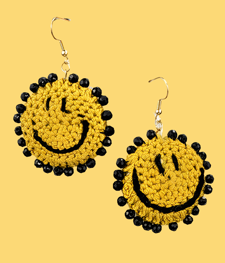 Crocheted smiley face earrings with black accents on a yellow background