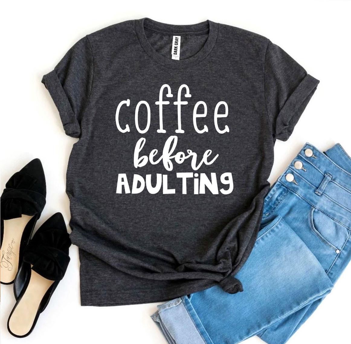 Dark gray t-shirt with 'coffee before adulting' text, paired with jeans and black shoes on a white background