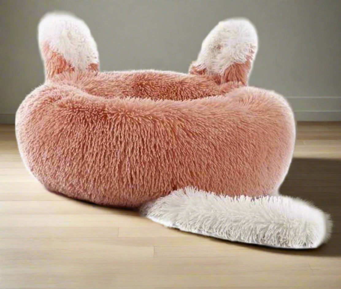 a plush pink pet bed with ears and tail design.