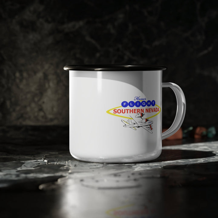 Honor Flight Southern Nevada white enamel campfire mug with black rim, featuring vintage airplane logo in red, yellow, and blue, durable lightweight coffee cup supporting veterans.