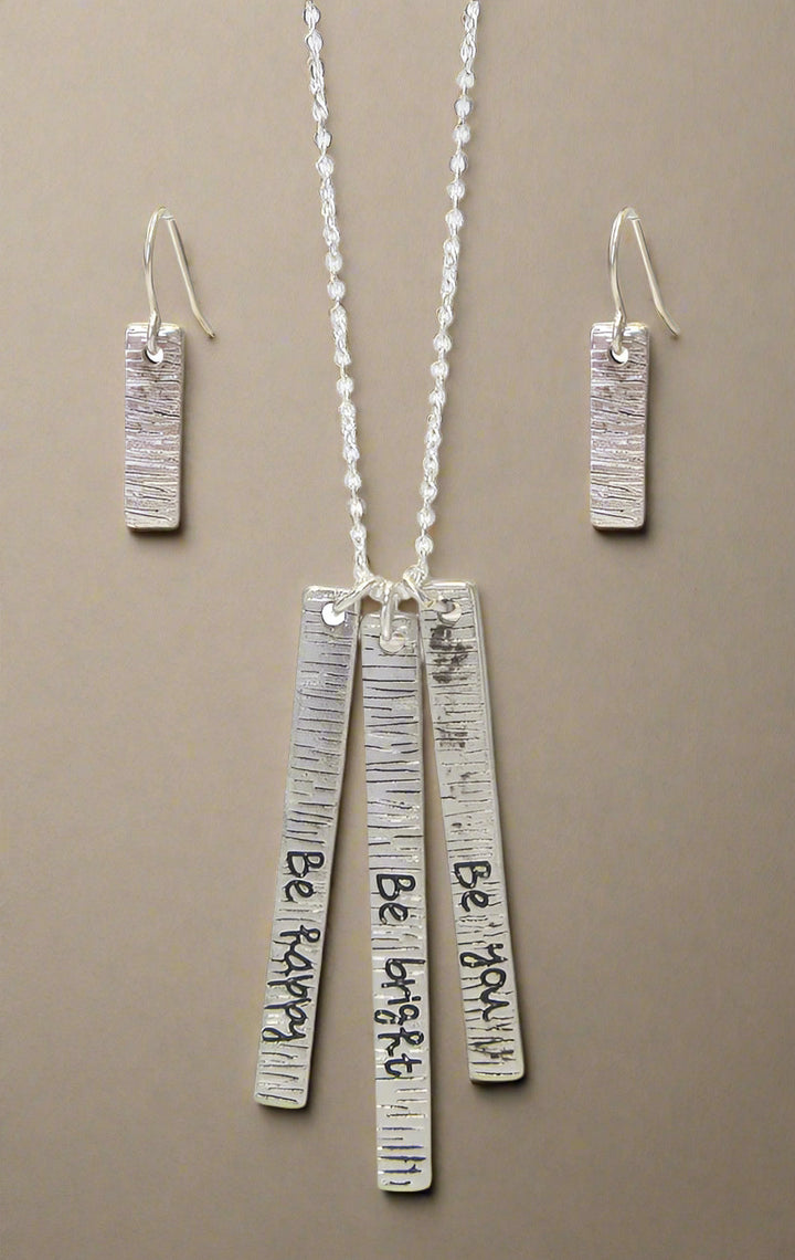 A silver-colored necklace set with a triple bar pendant and matching earrings, displayed against a white background.