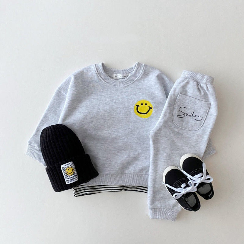 Gray sweatshirt with smiley face, gray sweatpants, black beanie, and black sneakers on a white background