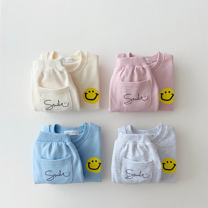Four children's sweatshirts in white, pink, blue, and gray with smiley face designs on a light gray background.