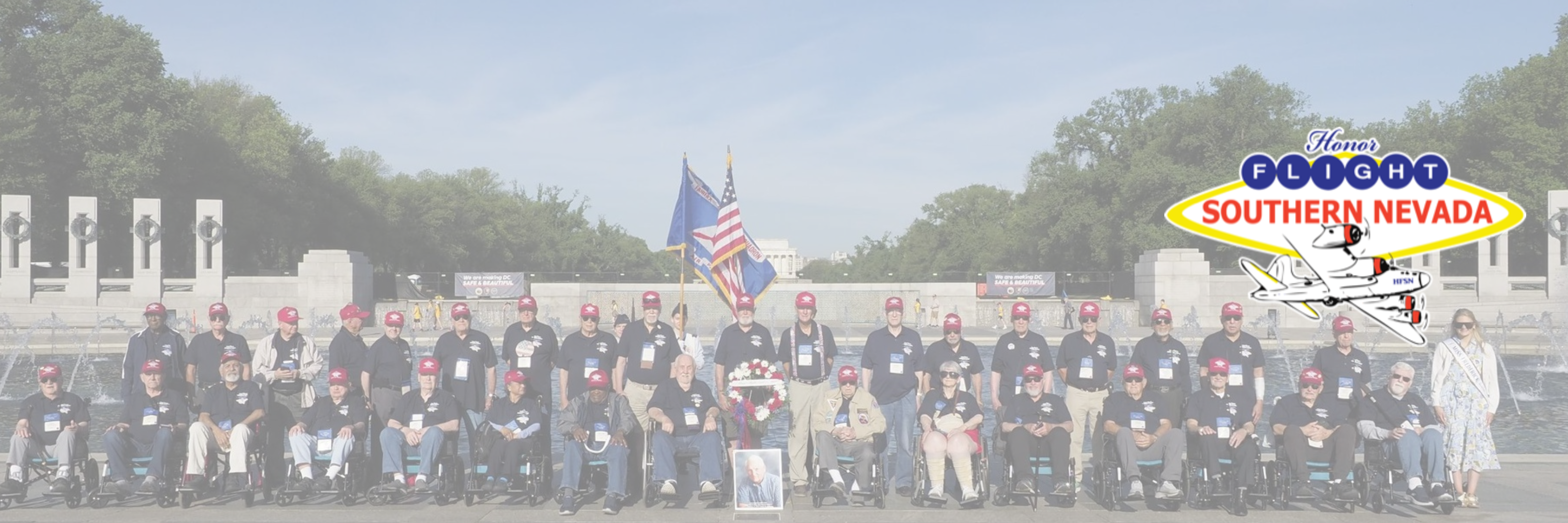 Honor Flight Southern Nevada honoring veterans at memorial with flags and honor guard.
