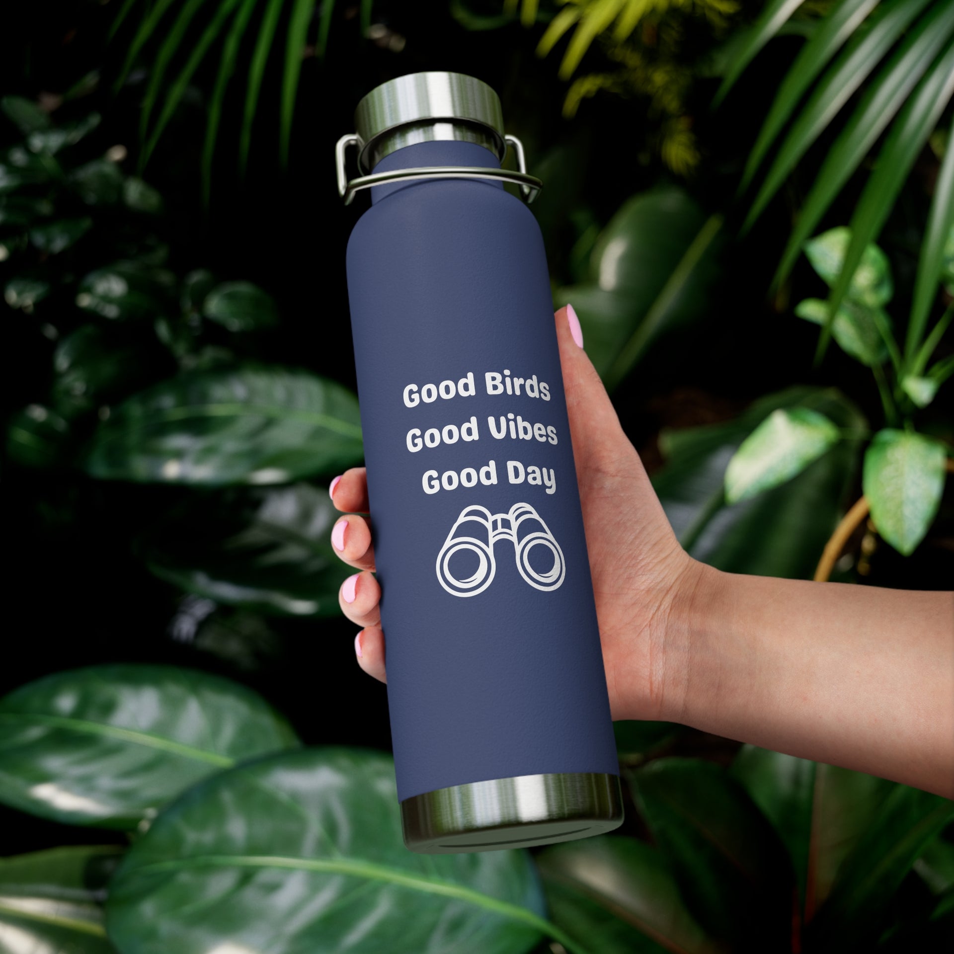 Birding copper vacuum insulated water bottle 22oz with bird binocular design in hand surrounded by green foliage