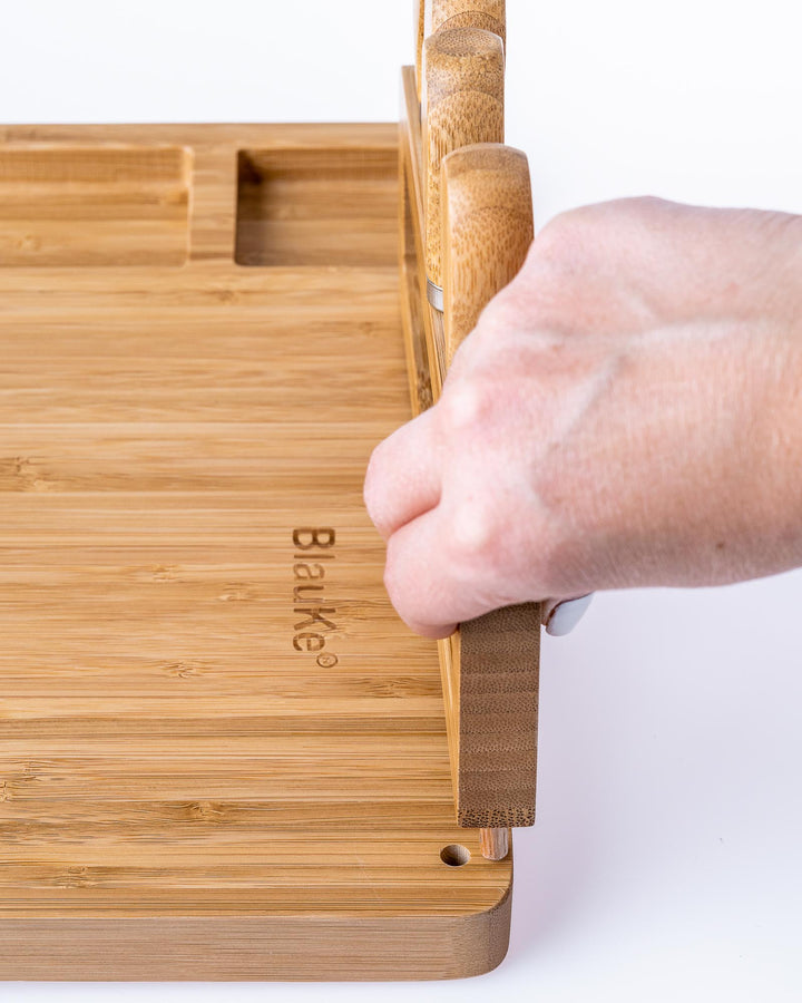 Bamboo cutting board with a hand holding it on a white background