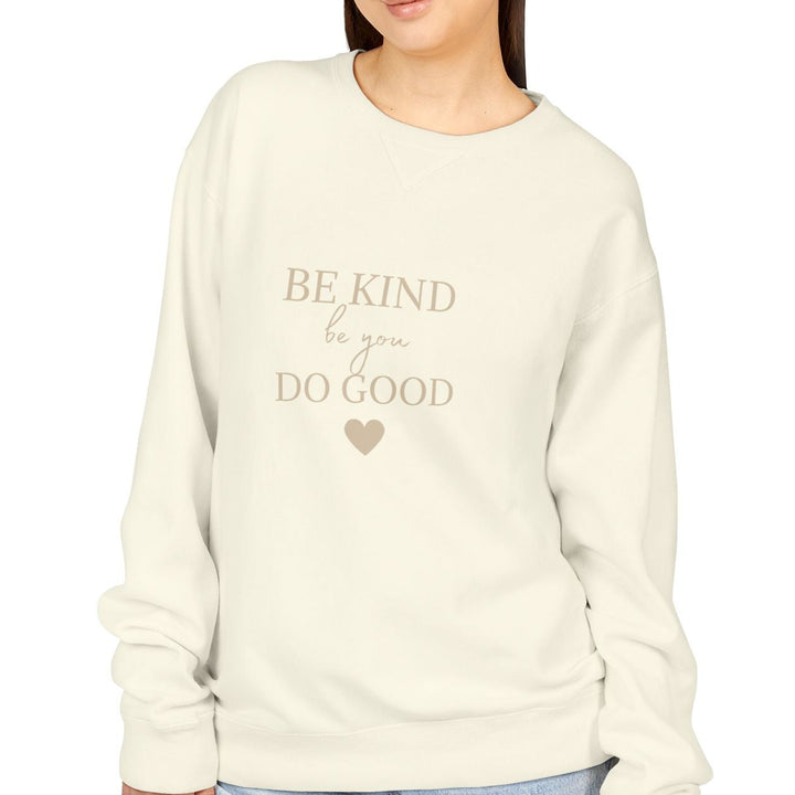 Be Kind Do Good Crewneck Sweatshirt model wearing a beige sweatshirt with the text 'BE KIND DO GOOD'.