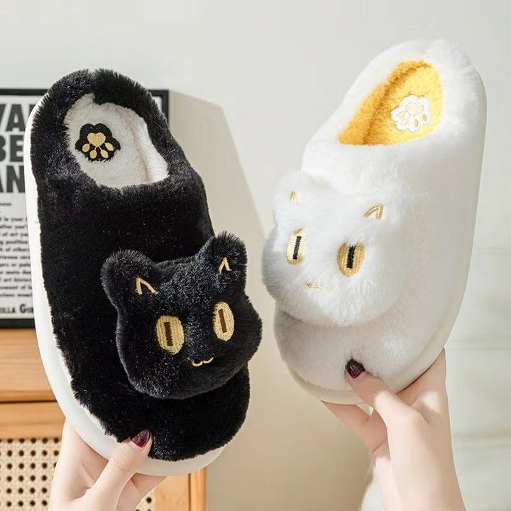 White cotton cat slippers with cute feline face design held in hand