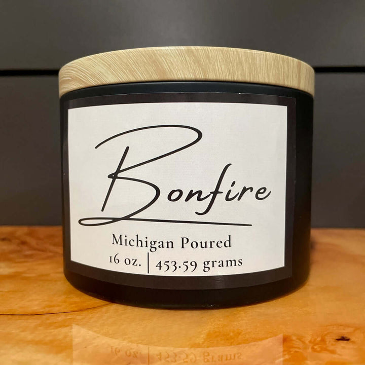Candle jar labeled 'Bonfire' with a wooden lid on a wooden surface.