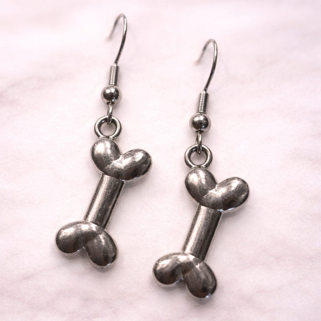 Silver dog bone dangle earrings on soft neutral background, hypoallergenic pet lover jewelry from the Sonya Lee collection.