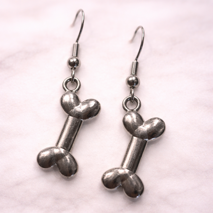 Silver dog bone dangle earrings on soft neutral background, hypoallergenic pet lover jewelry from the Sonya Lee collection.