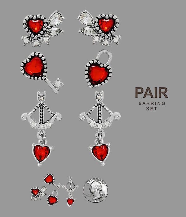 Set of three pairs of earrings with red heart stones on a white background