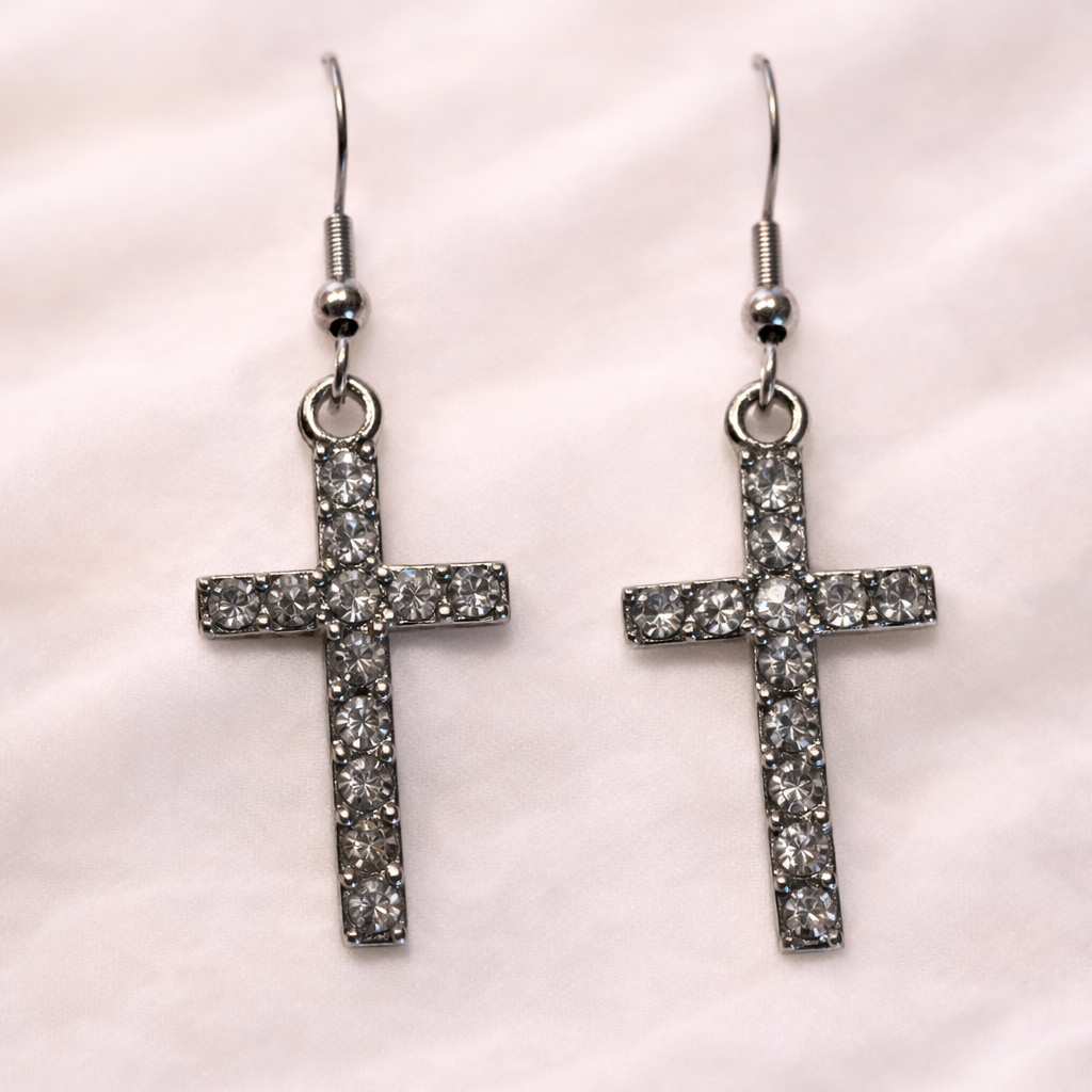 Silver rhinestone cross dangle earrings with hook backs on soft white background