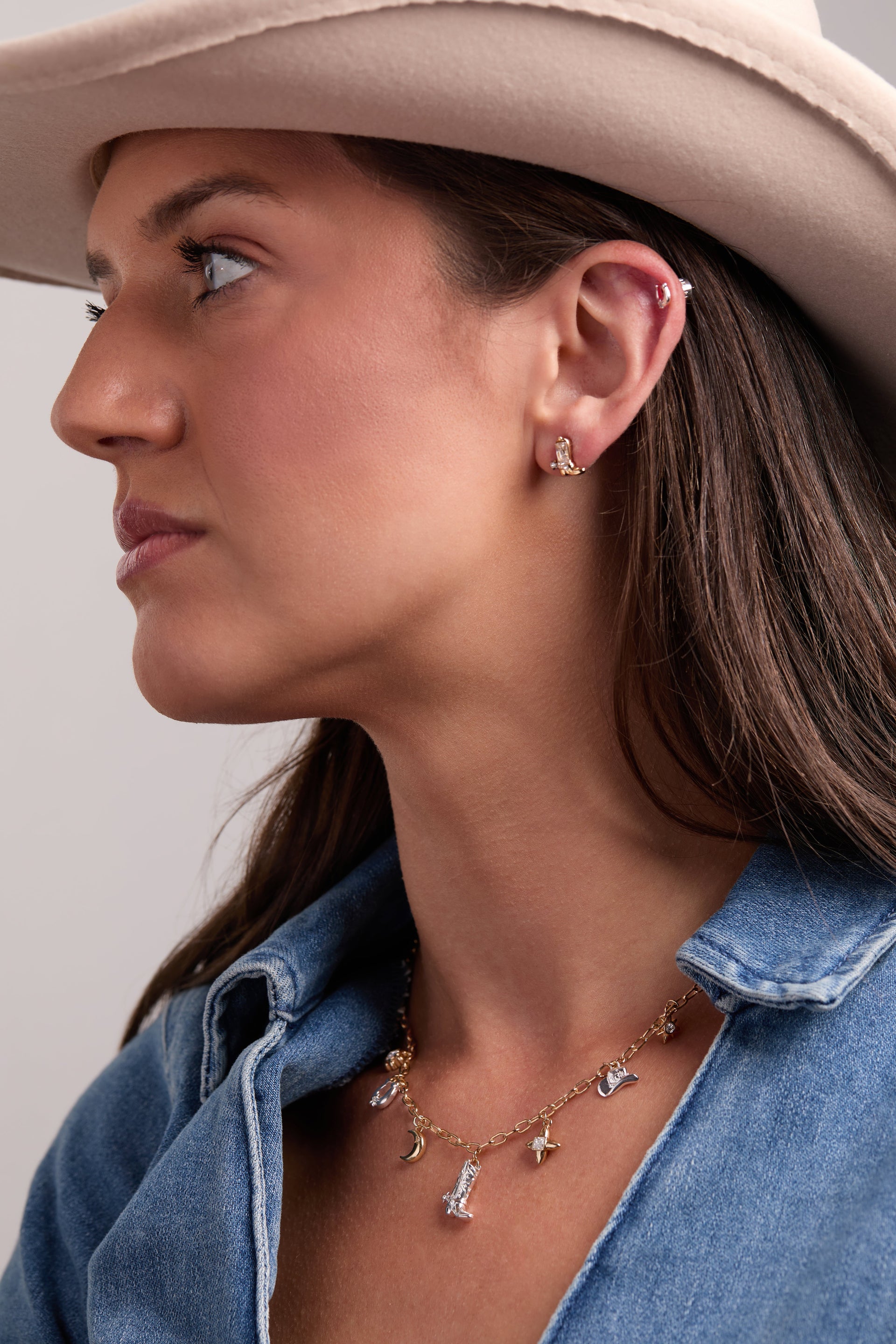 Woman wearing cowgirl earring studs Cowboy boots and Horseshoes with a necklace, showcasing Western elegance.