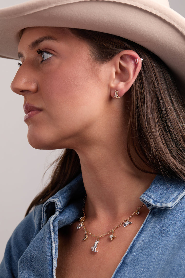Woman wearing cowgirl earring studs Cowboy boots and Horseshoes with a necklace, showcasing Western elegance.