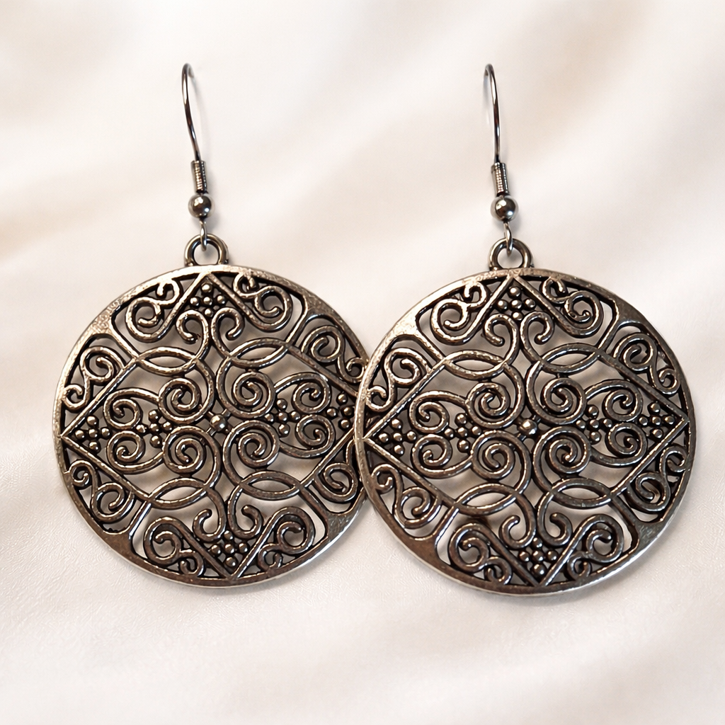 Pair of silver earrings with intricate patterns on a light background