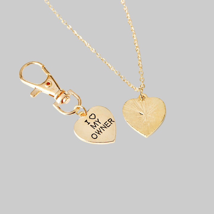 Gold heart-shaped necklace with 'I love my owner' tag on a white background