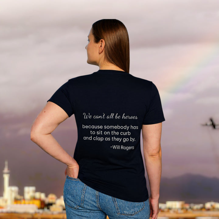 Person wearing a black t-shirt with a quote, standing against a cityscape with a rainbow.