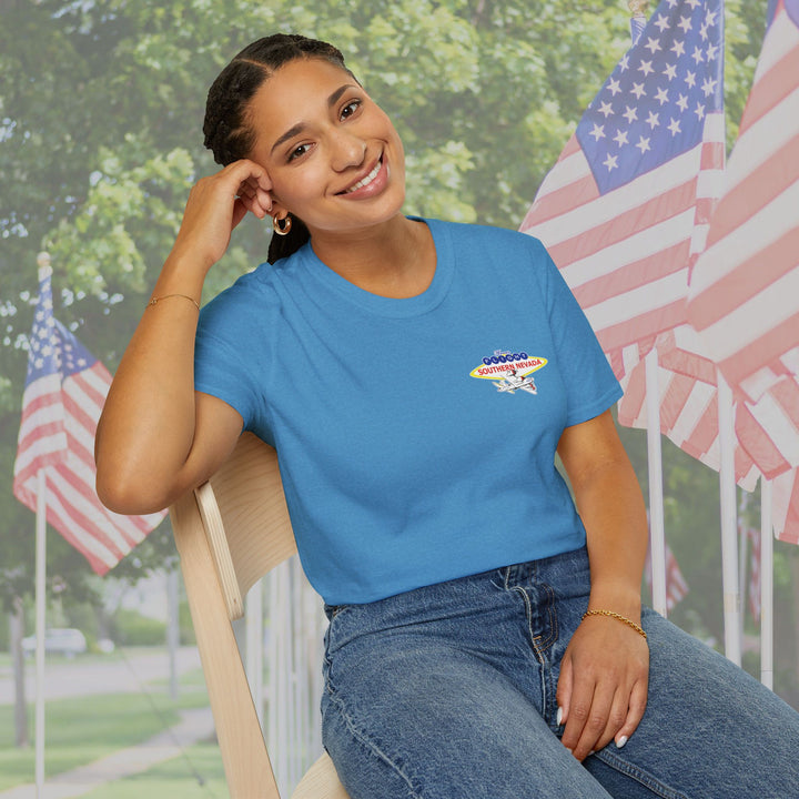 Woman wearing a blue t-shirt with a logo, sitting outdoors with American flags in the background.