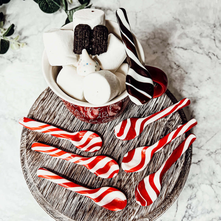Hot chocolate with marshmallows and candy canes on a wooden board.