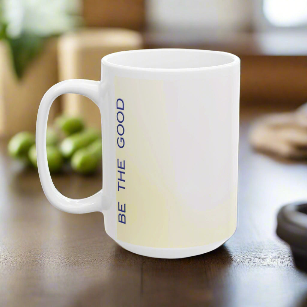 Back side of a white mug that says "Be the good" running up and down the mug vertically 