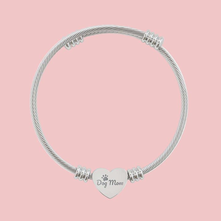 Engravable heart cuff bracelet featuring a charm that says 'Dog Mom' on a sleek cable wire design.