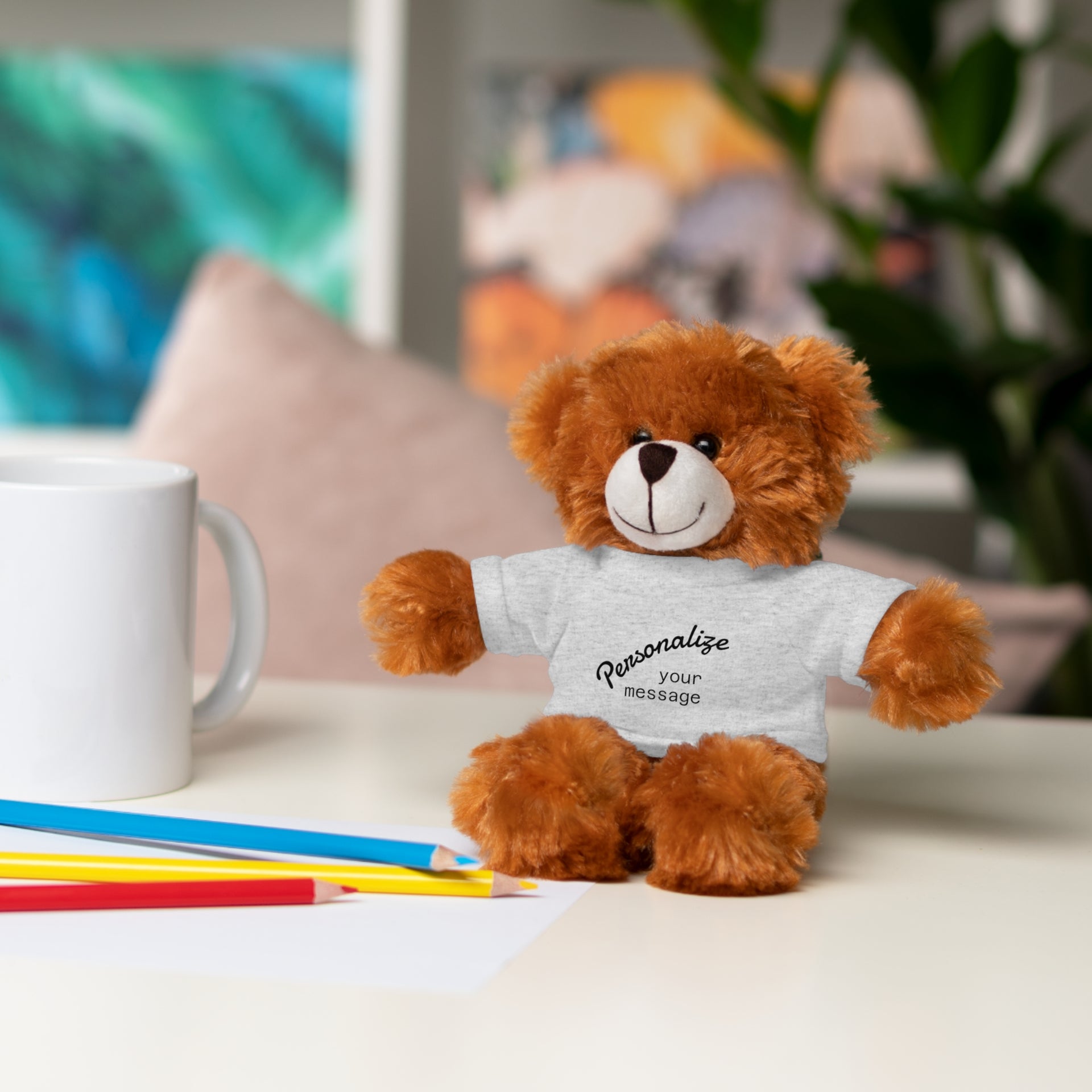 Personalized stuffed animal gift cuddly bear with customizable shirt on a table with colorful pencils and mug
