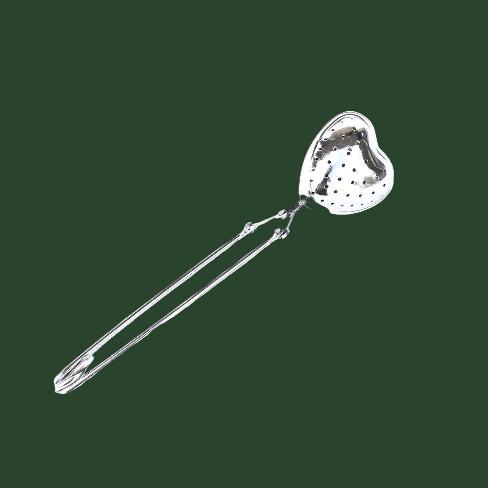 Reusable stainless steel heart infuser in front of a static green background