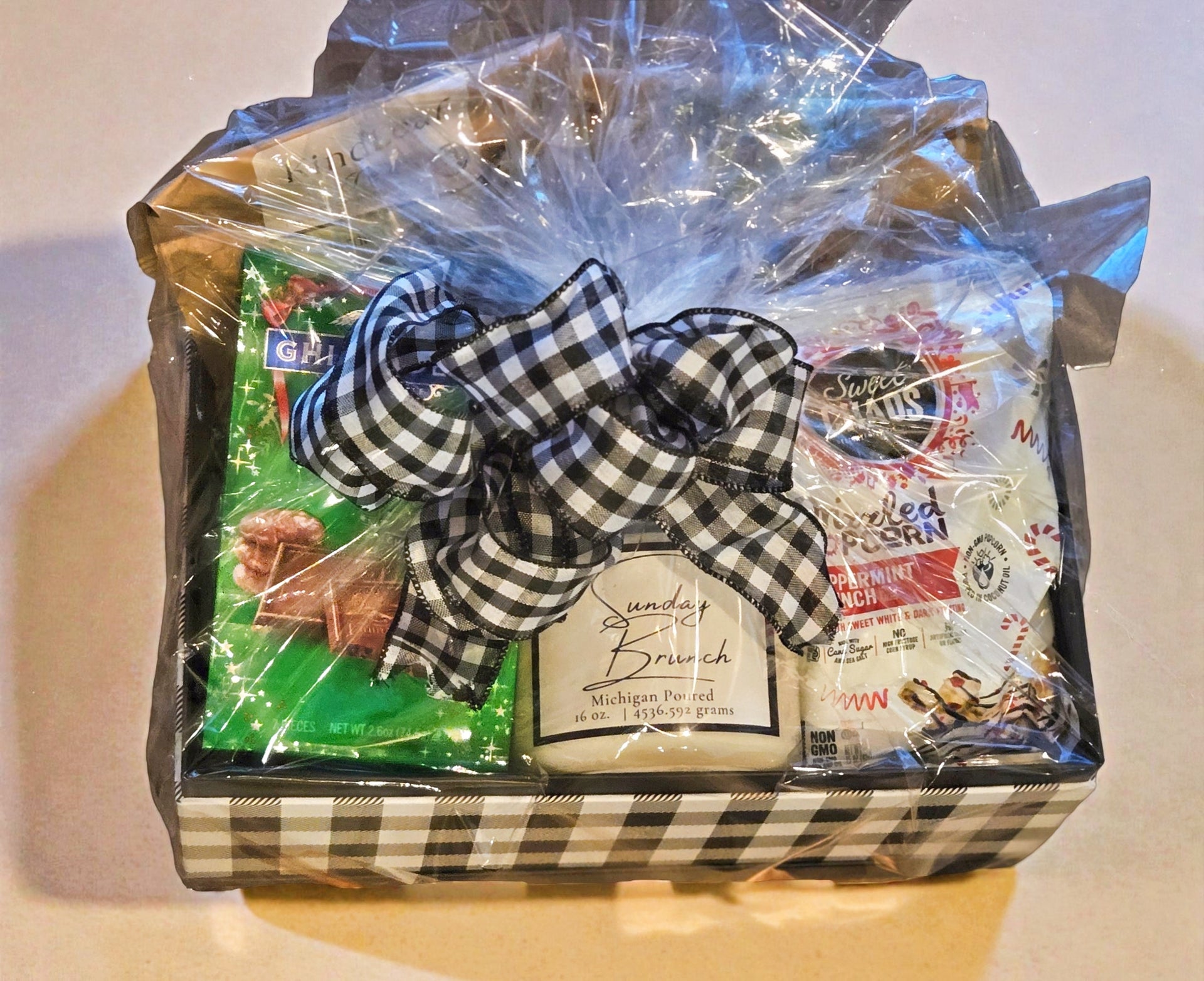 Tea and candle Gift basket with a checkered ribbon on a white surface