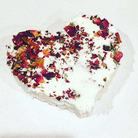 Heart-shaped bath bomb with colorful dried flowers on a white background