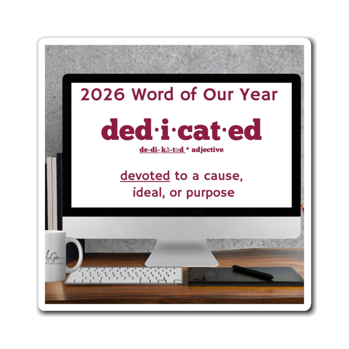 Computer monitor displaying '2026 Word of Our Year: dedicated' on a desk with a mug and keyboard.