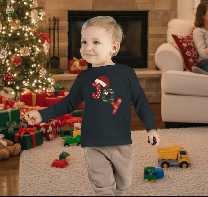 Child wearing a black long-sleeve shirt with a Christmas design