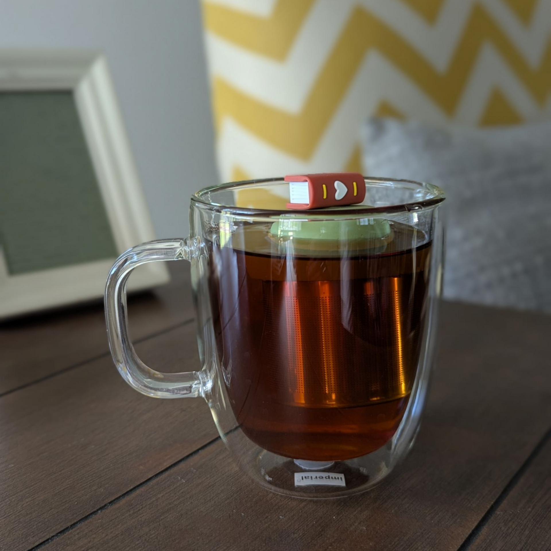 Brown book-shaped floating tea infuser with stainless steel mesh strainer brewing loose leaf tea, perfect for book lovers and tea enthusiasts.