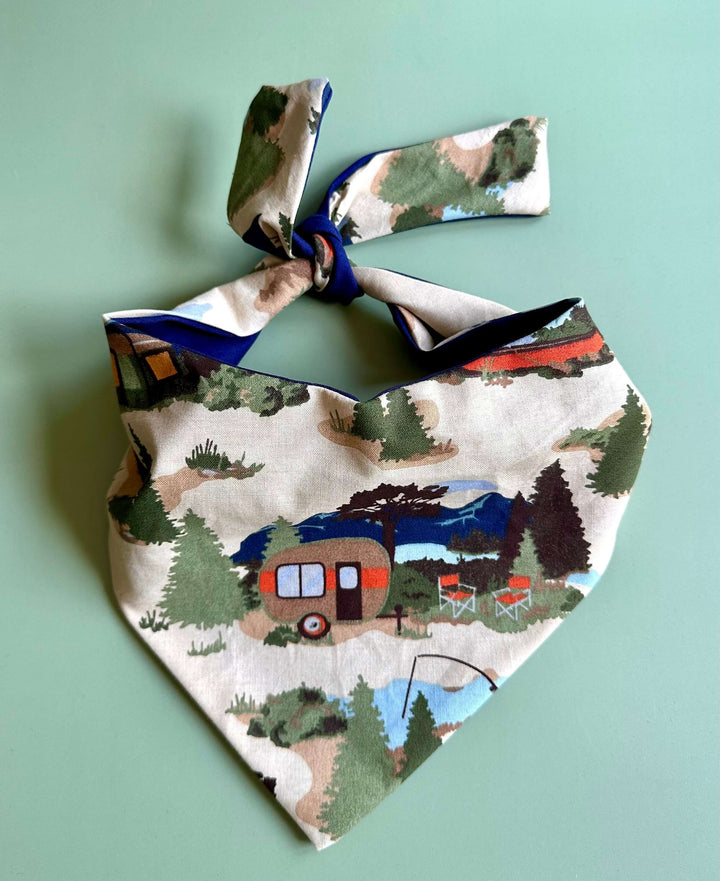 Camping dog bandana with retro camper, lake, mountain, and fishing print displayed flat on mint green background
