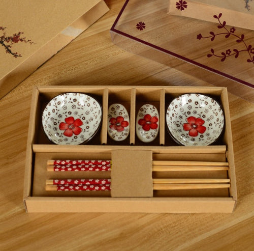 Set of ceramic dishes with floral design in a wooden box on a wooden surface