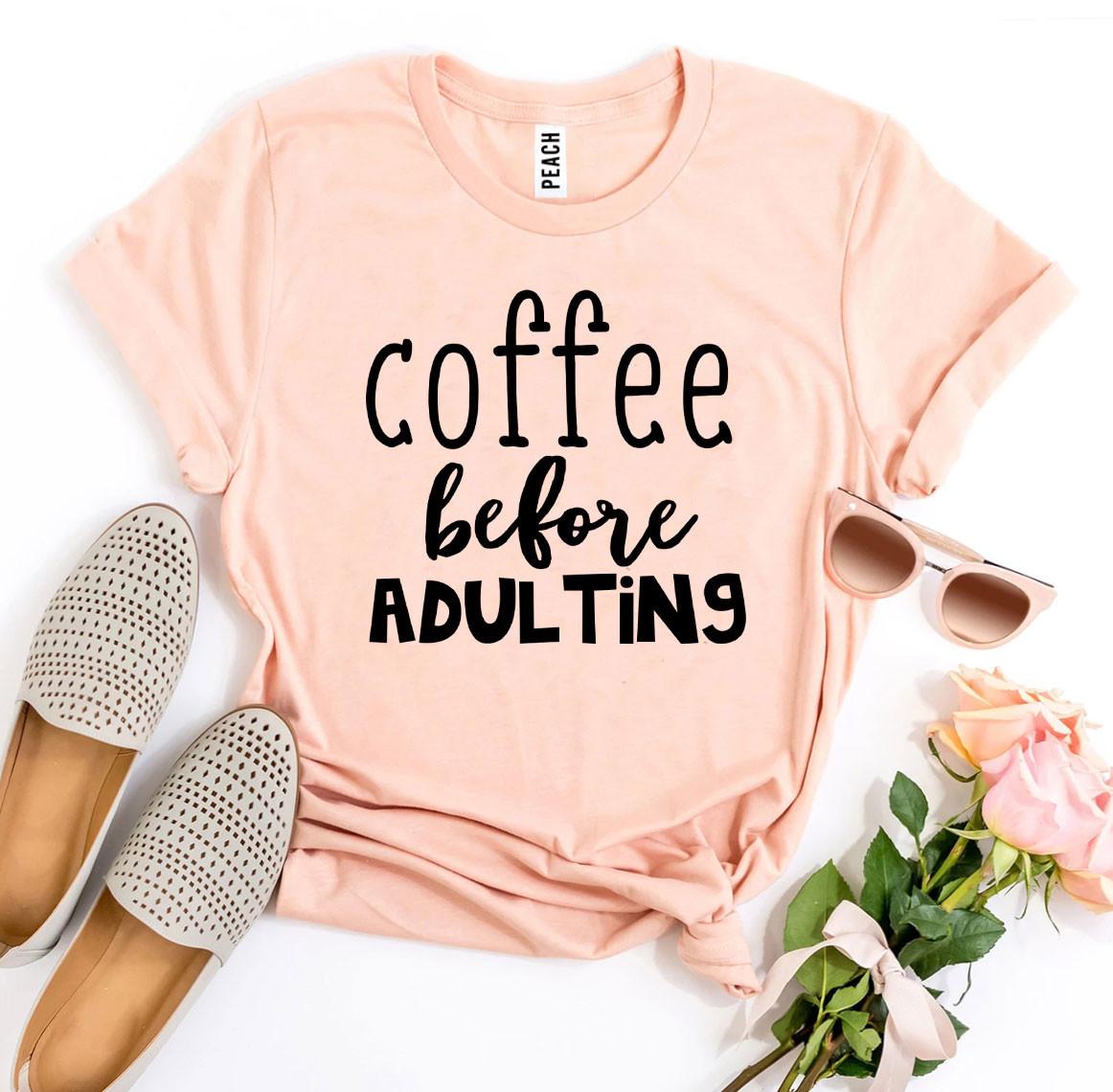 Pink t-shirt with 'coffee before adulting' text, accompanied by flat shoes, sunglasses, and flowers on a white background.