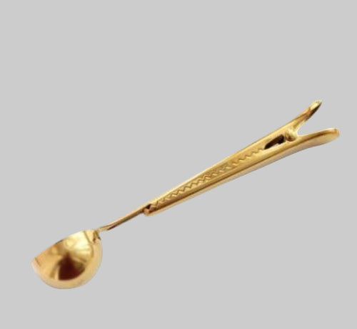 Stainless steel coffee clip spoon in gold finish on gray background
