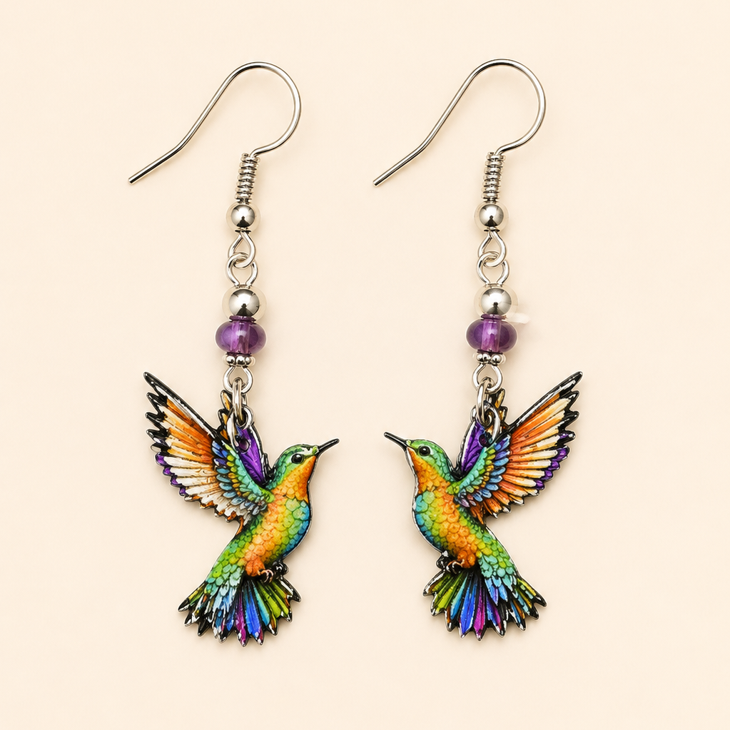 Colorful hummingbird dangle earrings featuring vibrant rainbow-colored birds and purple bead accents on a soft cream background. Lightweight bird lover jewelry.
