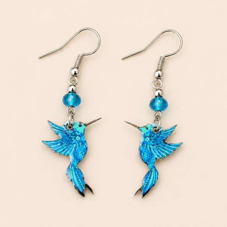 Blue hummingbird dangle earrings with turquoise bead accents displayed on a soft cream background.