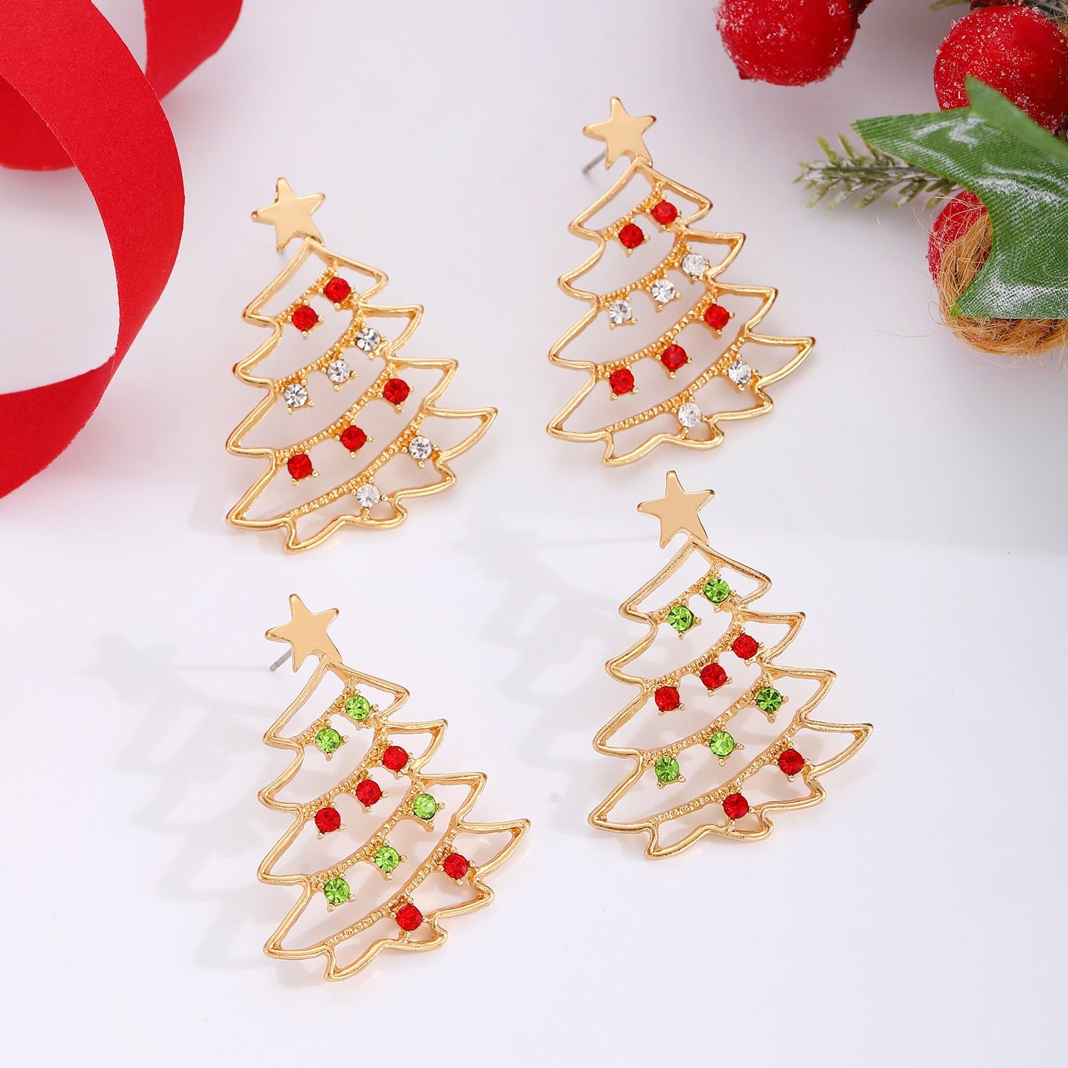 Gold Christmas tree earrings with red and green accents on a white background