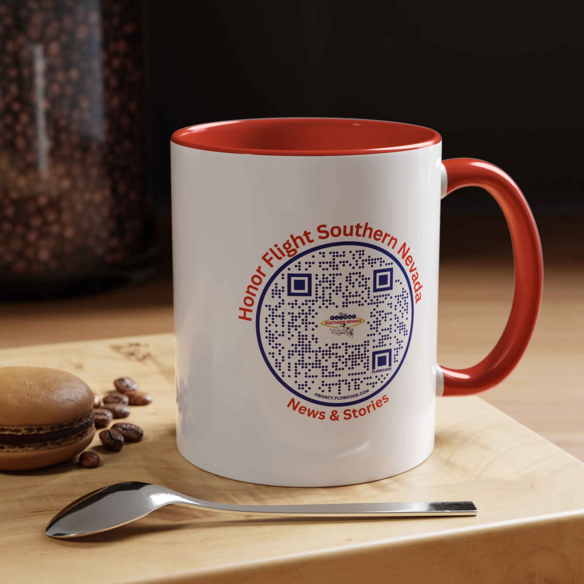 A two-tone ceramic coffee mug with a white body and red handle and interior. The mug has a printed design featuring the Honor Flight Southern Nevada logo.