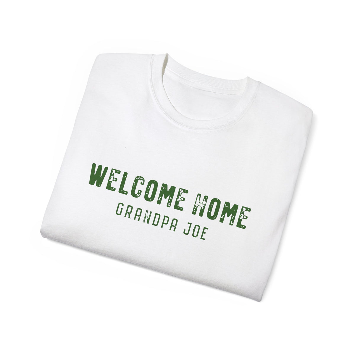 A folded white crewneck t-shirt with 'WELCOME HOME GRANDPA JOE' printed in distressed green text on the front, displayed on a clean white background.