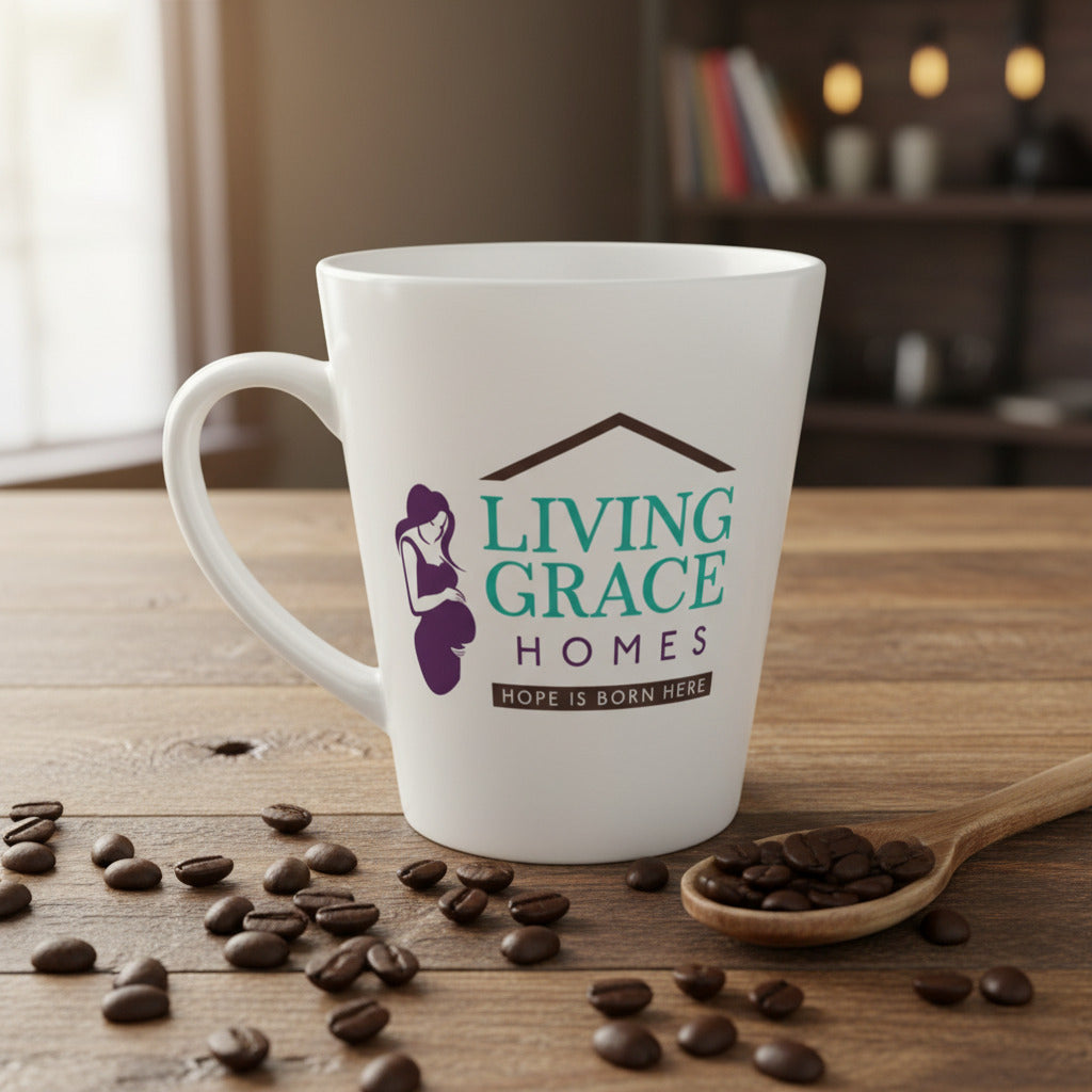 White ceramic mug with the Living Grace Homes logo and the phrase “Hope is born here,” surrounded by coffee beans and a wooden spoon on a rustic table. Inspirational nonprofit mug supporting mothers and families in need.