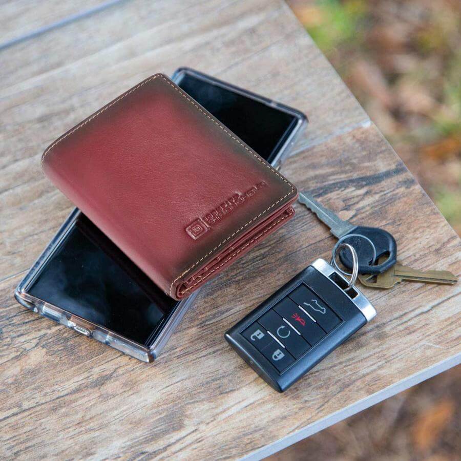 Brown RFID leather wallet, phone case, and car keys on a wooden surface