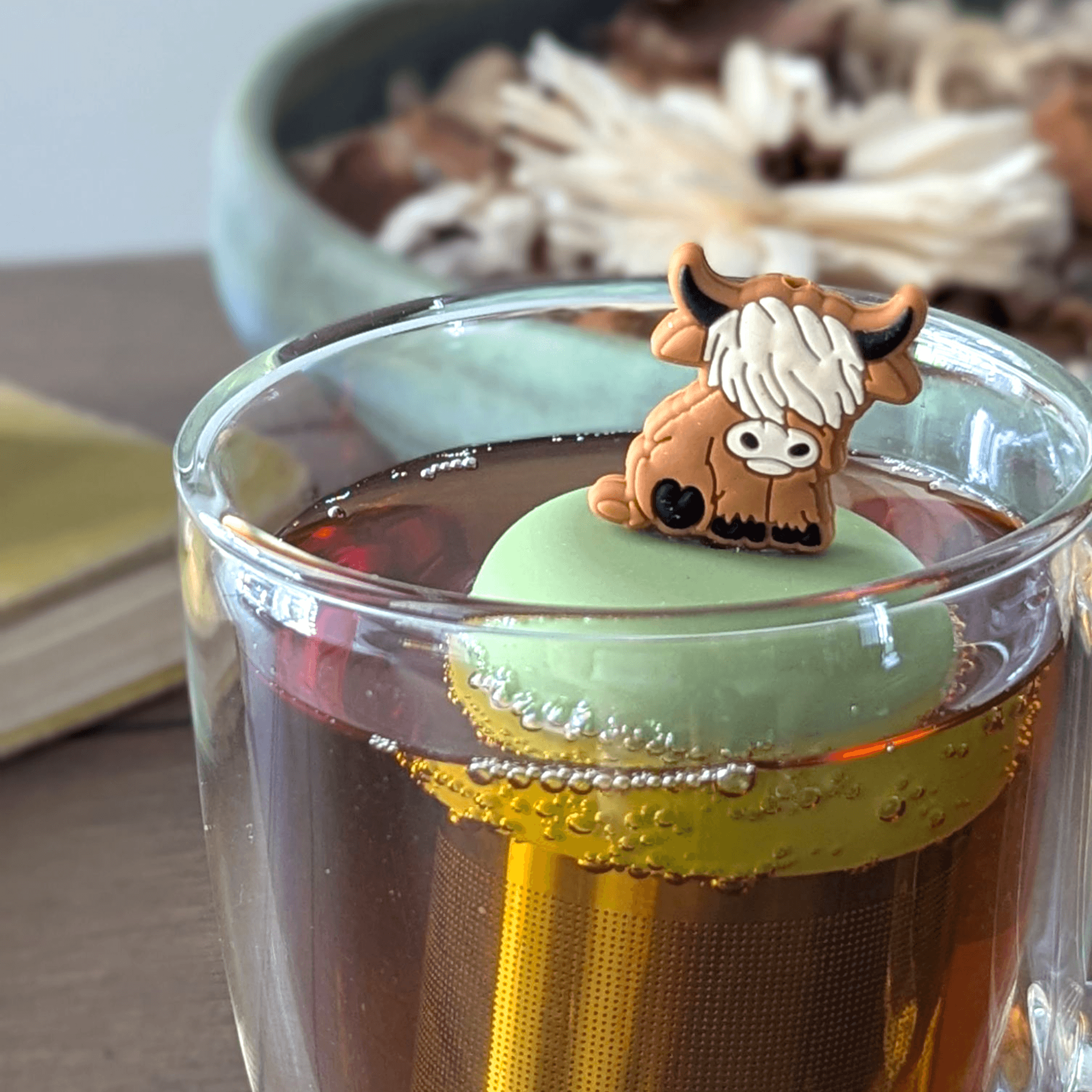 Floating Adult Highland Cow Tea Infuser in a cup of tea, perfect for brewing loose leaf tea with fun and style.