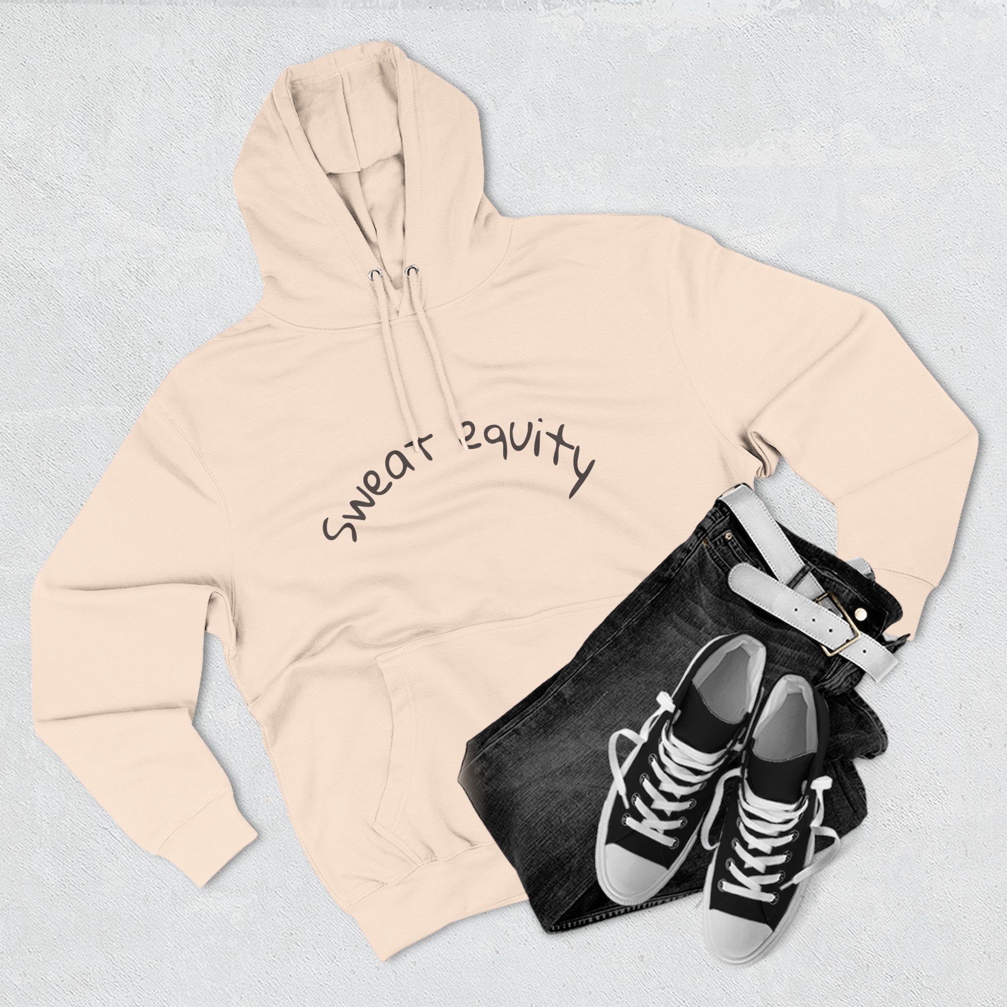 Beige “Sweat Equity” hoodie laid flat with black jeans, belt, and sneakers, unisex motivational sweatshirt promoting fitness, hustle, and entrepreneur lifestyle fashion.