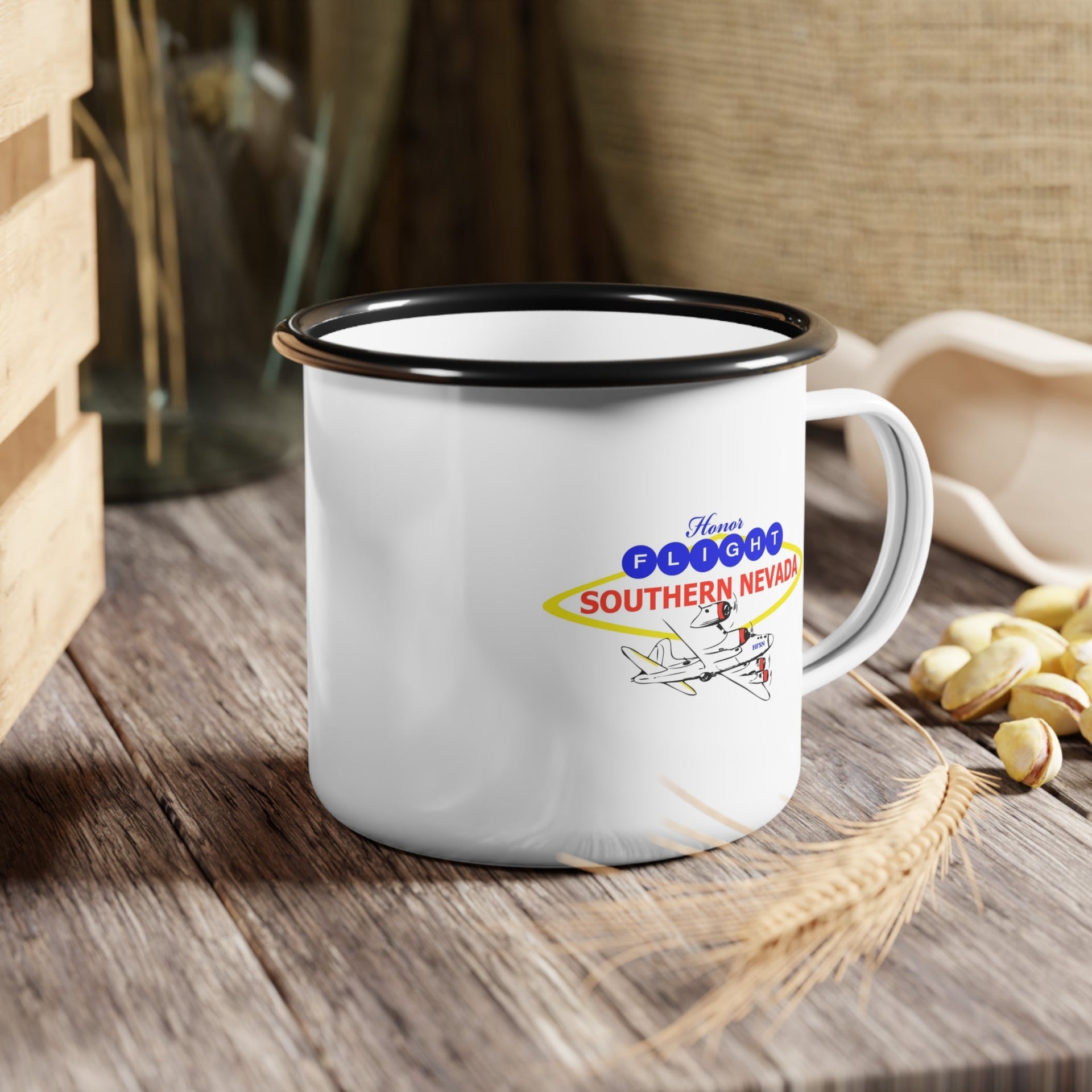 Honor Flight Southern Nevada white enamel campfire mug with black rim, featuring vintage airplane logo in red, yellow, and blue, durable lightweight coffee cup supporting veterans.